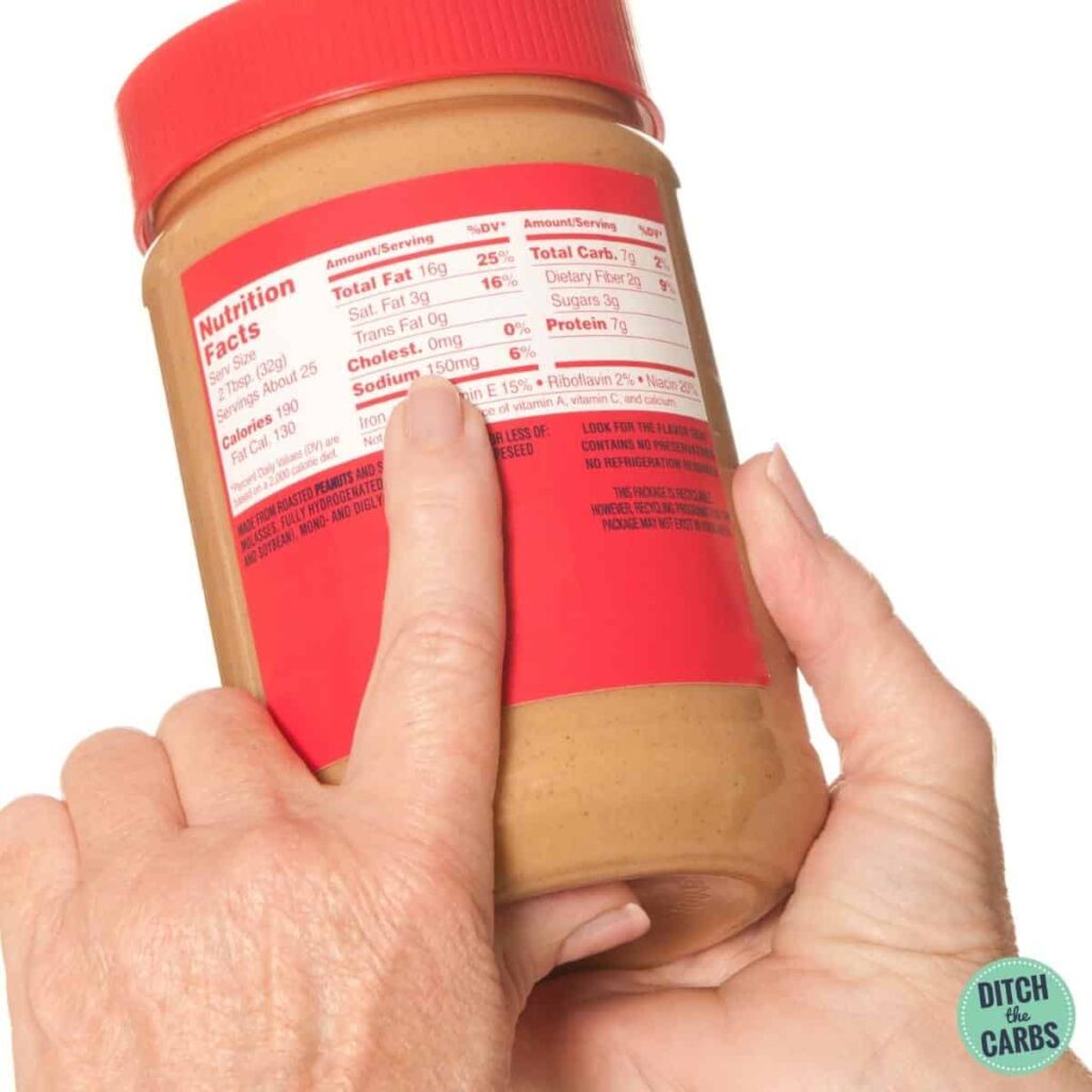 food label showing carbohydrates in peanut butter held by hand